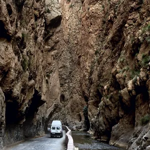 A white vehicle drives through the narrow section of Dades Gorge