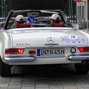A white vintage Mercedes convertible seen from the rear in an urban setting