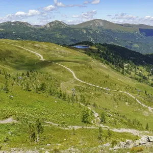 Wide open landscape with mountain trail and wooded hills in the background