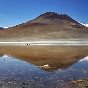 Wide panorama of mountains with reflecting lake and clear sky above the scene