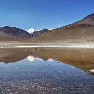 Wide panoramic view of mountains reflecting in the still lake