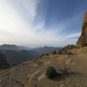 Wide, rocky landscape with views of distant mountains under blue sky Wide, rocky landscape with views of distant mountains under blue sky