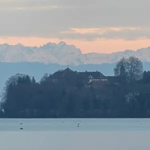 Wide view of mountains and lake under pastel colored sky Wide view of mountains and lake under pastel colored sky