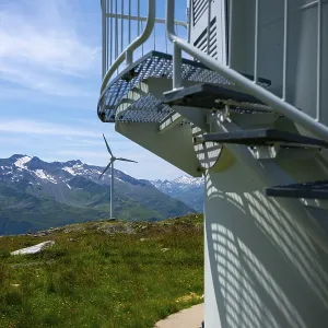 Wind Turbine and Column and Mountain with Glacier in the Swiss Alps and Against Blue Sky
