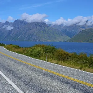 Winding road along a lake with mountains in the background
