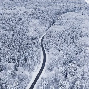 Winding road through snowy winter forest from the air