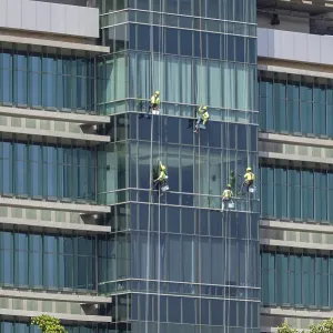 Window cleaners work as a team to clean the glass front of a hospital in downtown Bangkok Window cleaners work as a team to clean the glass front of a hospital in downtown Bangkok