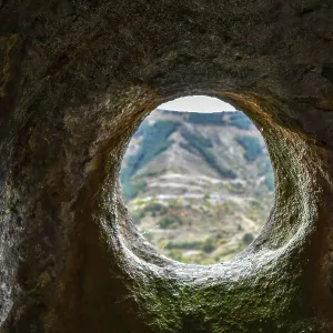 A window in a sandstone cave with a view of the opposite mountain