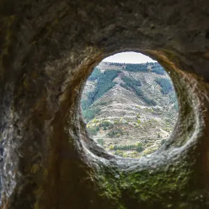 A window in a sandstone cave with a view of the opposite mountain