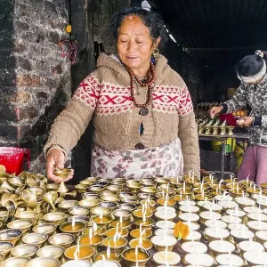 A woman is arranging butter lamps at a temple in Boudha A woman is arranging butter lamps at a temple in Boudha