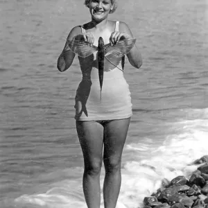 Woman on the beach in a bathing suit with flying fish