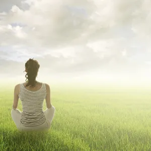 Woman of brunet hair sit on grassland against sunrise or sunset