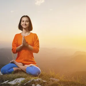 Woman doing yoga and meditation in the mountains at sunset