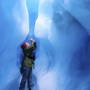 Woman photographing in a ice cave in Fox Glacier Woman photographing in a ice cave in Fox Glacier