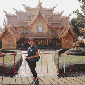 A woman posing in front of an ornate traditional thai temple with landscaped garden in Wat Rong Khun or White Temple A woman posing in front of an ornate traditional thai temple with landscaped garden in Wat Rong Khun or White Temple