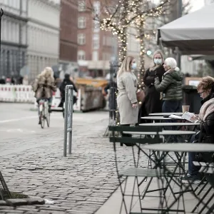 A woman reads at an outdoor cafe as people converse nearby A woman reads at an outdoor cafe as people converse nearby