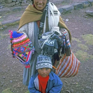 A woman with a small child sells souvenirs to tourists at the Sillustani ruins on Lake Umayo near Puno