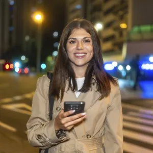 Woman smiling brightly and holding a smartphone Woman smiling brightly and holding a smartphone