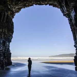 Woman standing in the giant entrance of Cathedral caves in backlit