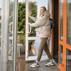 A woman steps out of a contemporary building on a cool day