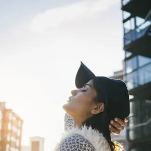 Une femme coiffée d'un chapeau élégant et vêtue d'un manteau à motifs fait face au soleil. Une femme coiffée d'un chapeau élégant et vêtue d'un manteau à motifs fait face au soleil.