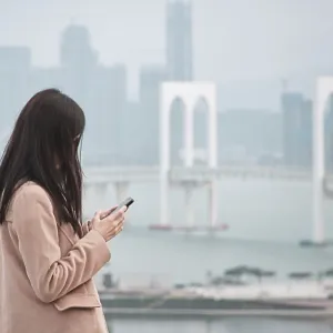 Woman, using phone with Sai Van Bridge in the background Woman, using phone with Sai Van Bridge in the background