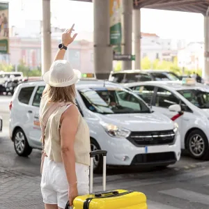 Woman with a yellow suitcase standing at a busy transportation hub