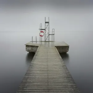 Wooden jetty with diving platform and lifebelt at lake Sommen, foggy, Nora, Sweden, Europe Wooden jetty with diving platform and lifebelt at lake Sommen, foggy, Nora, Sweden, Europe
