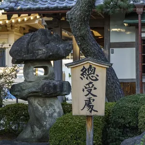 A wooden sign stands next to a large rock in a Japanese garden A wooden sign stands next to a large rock in a Japanese garden