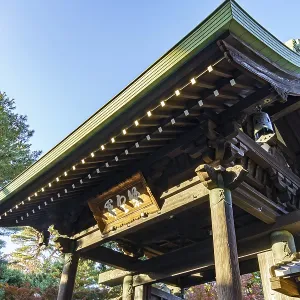 Wooden torii structure at a Japanese temple surrounded by trees and clear skies Wooden torii structure at a Japanese temple surrounded by trees and clear skies