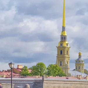 Yellow church tower towering in cloudy sky surrounded by trees and cityscape