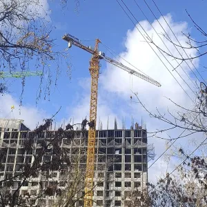 A yellow crane is building a house out of concrete slabs