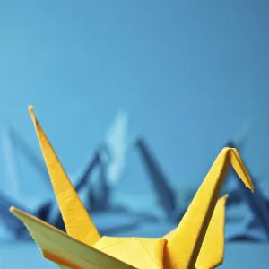 Yellow origami crane on a blue background with other blurry cranes Yellow origami crane on a blue background with other blurry cranes