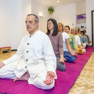 Yoga teacher leading a group of women meditating in line in lotus position and eyes closed Yoga teacher leading a group of women meditating in line in lotus position and eyes closed