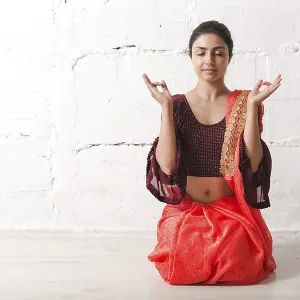 Young adult indian woman in sari meditating yoga zen like with ok sign mudra gesture