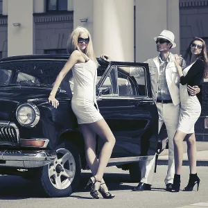 Young fashion people next to vintage car