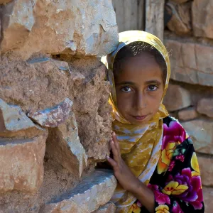 Young girl, berberine, looking curiously from behind a wall Young girl, berberine, looking curiously from behind a wall