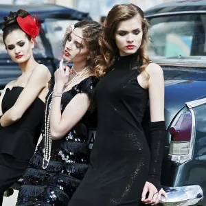 Three young girl in retro style dress near old classic vintage cars