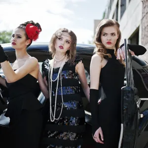 Three young girl in retro style dress near old classic vintage cars