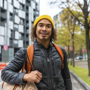 Young man with curly hair in a yellow beanie and leather jacket
