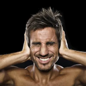 Young man holding his hands against his ears Young man holding his hands against his ears