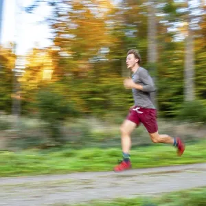 Young man jogging in the autumnal forest