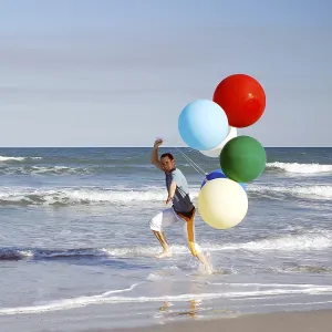 Young man with large colourful balloons at the beach