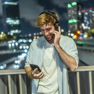Young man smiling and listening to music through wireless headphones Young man smiling and listening to music through wireless headphones