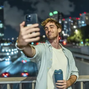 Young man smiling and taking a selfie with a smartphone Young man smiling and taking a selfie with a smartphone