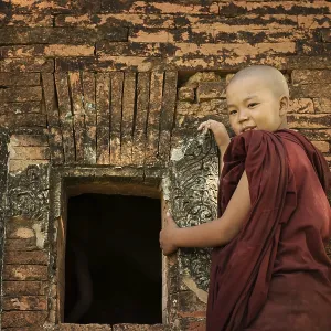 Young novice monk standing outside Buddhist temple Young novice monk standing outside Buddhist temple