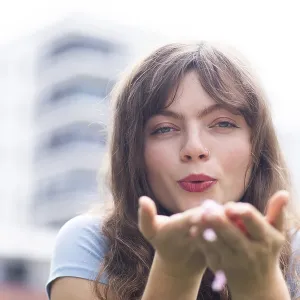 Young woman with long hair blowing into her hands