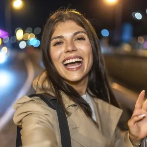 Young woman smiling and taking a nighttime selfie on a vibrant city street Young woman smiling and taking a nighttime selfie on a vibrant city street