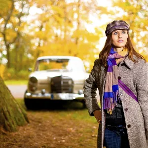 Young woman standing in front of a vintage car Young woman standing in front of a vintage car