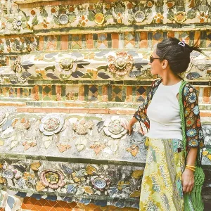 Young woman traveler blogger pose by beautiful famous buddhist temple Wat Arun - famous travel destination in Bangkok